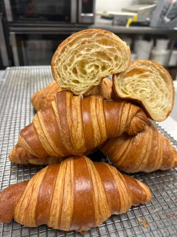 Stack of croissants, one torn open to show the layers
