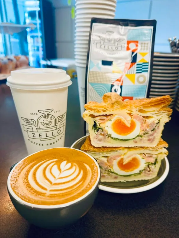 Bacon and egg pie cut in half beside a Zello coffee